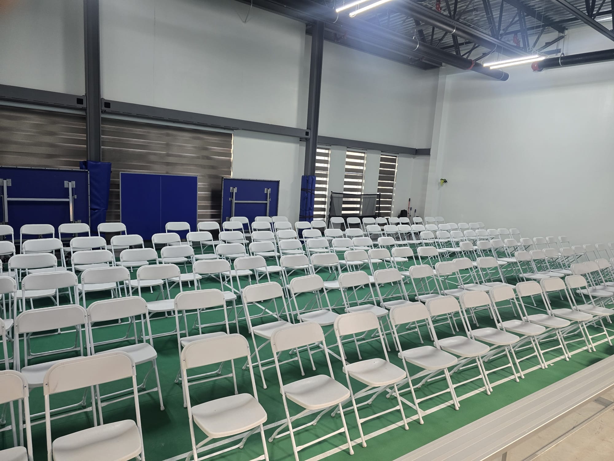Rows of white folding chairs prepared for an indoor event