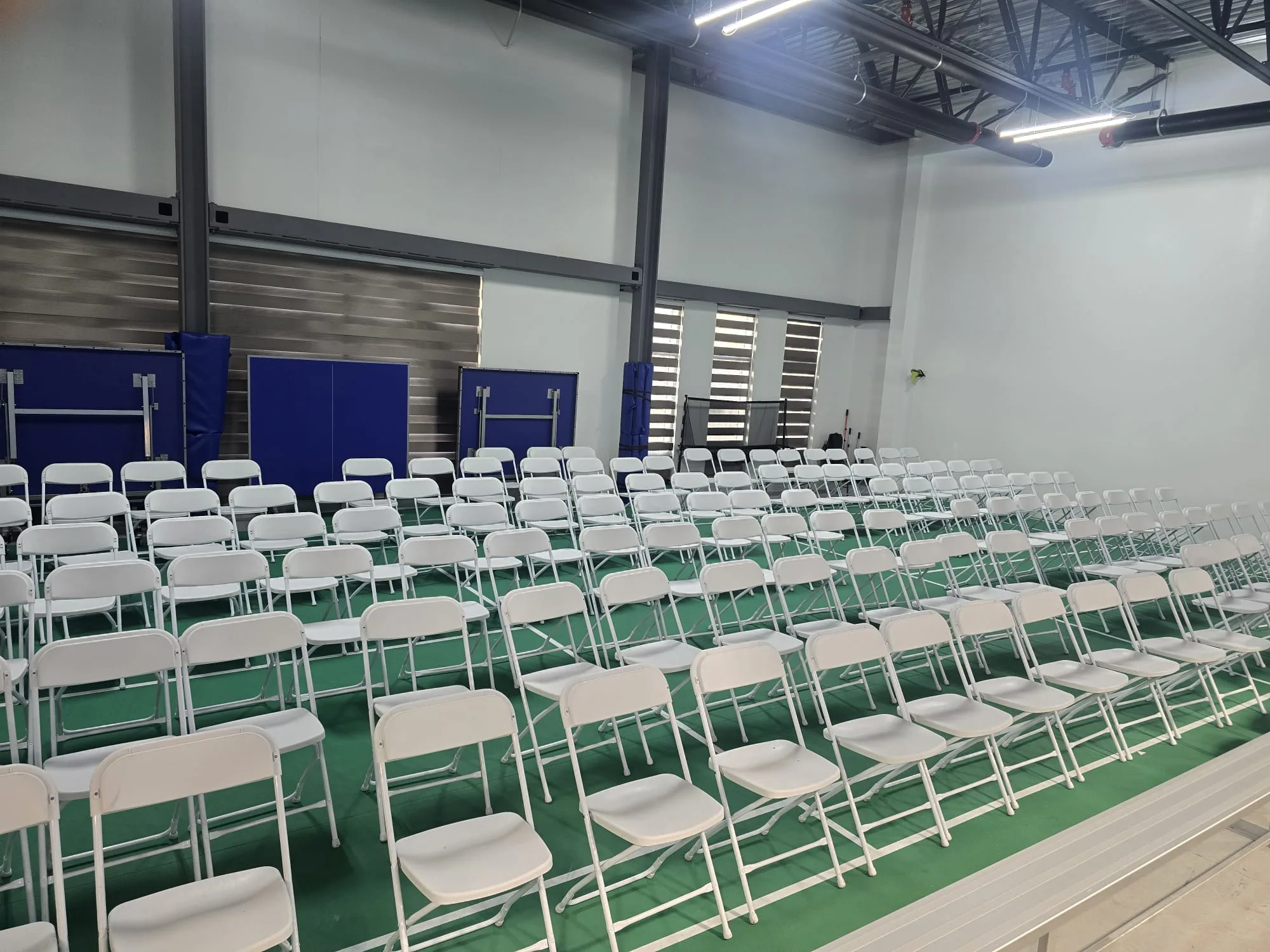 Rows of white chairs arranged by Gather & Go Rentals in a large indoor community space