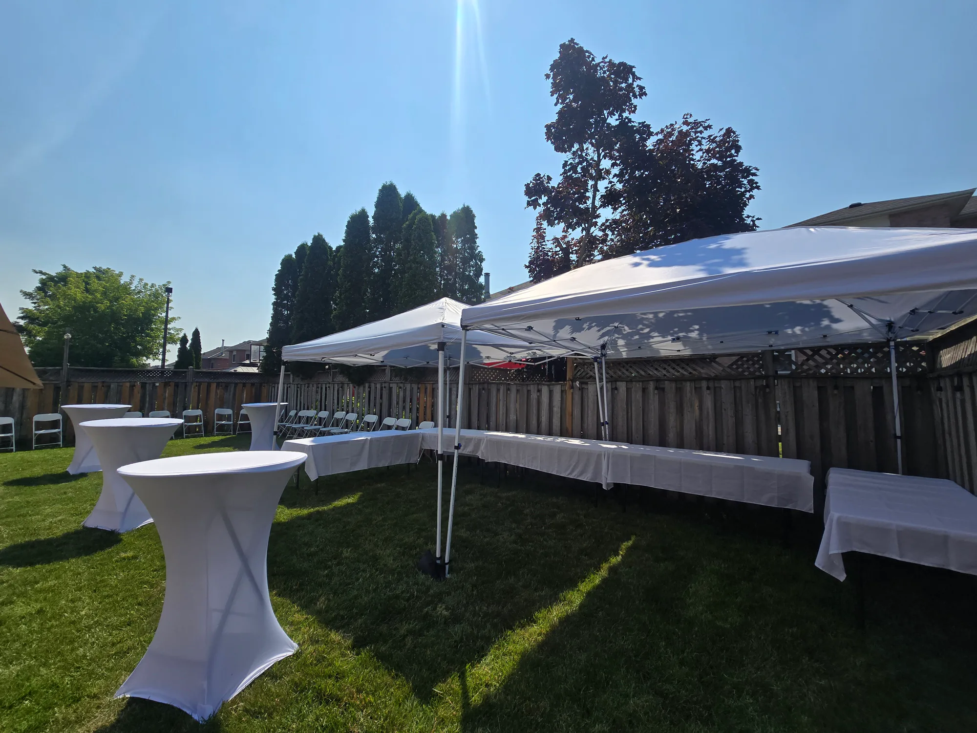 White canopies, linen-covered cocktail tables, and chairs arranged by Gather & Go Rentals outdoors